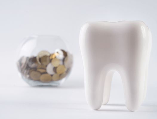 Glass bowl of coins and large model tooth