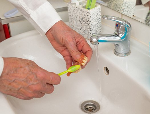 person cleaning dentures
