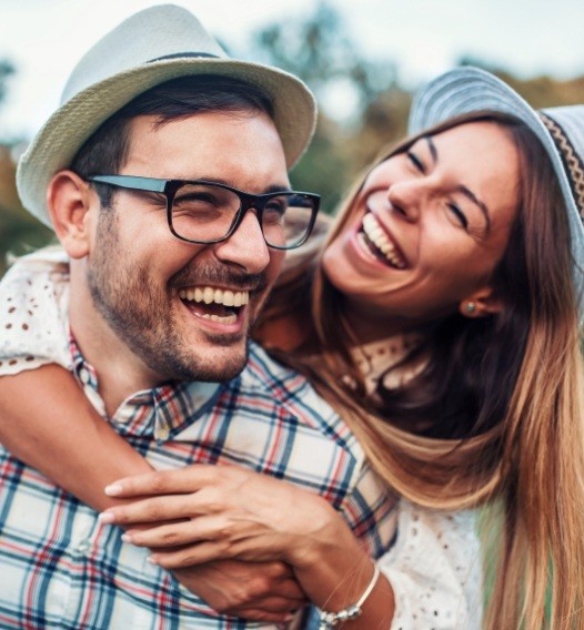 Man and woman smiling after dental services