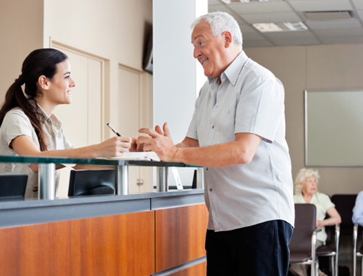 a man speaking with a front desk dental office staff member