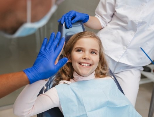 Young girl giving dentist a high five after dental checkup and teeth cleaning visit