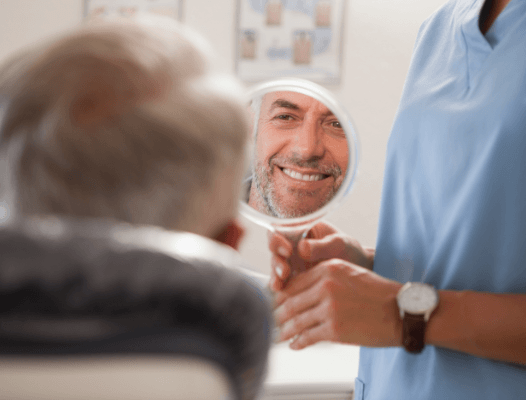 Man looking at smile in mirror after dental bonding treatment