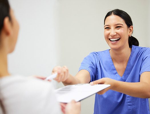 a front desk staff member giving a patient forms