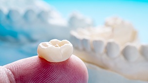 a finger holding a dental crown