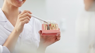 Dentist pointing to dental implant supported dental crown model