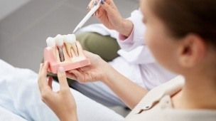 Dentist and patient looking at dental implant model