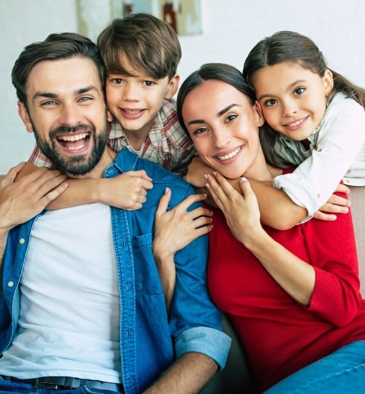 Mother father and two children smiling together after family dentistry