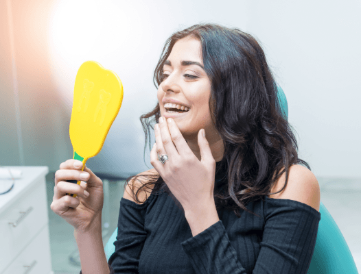 Woman looking at smile after gum recontouring treatment