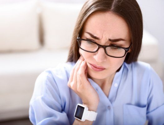 Woman experiencing jaw pain caused by teeth grinding