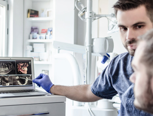 a dentist showing a patient his X-rays on a computer