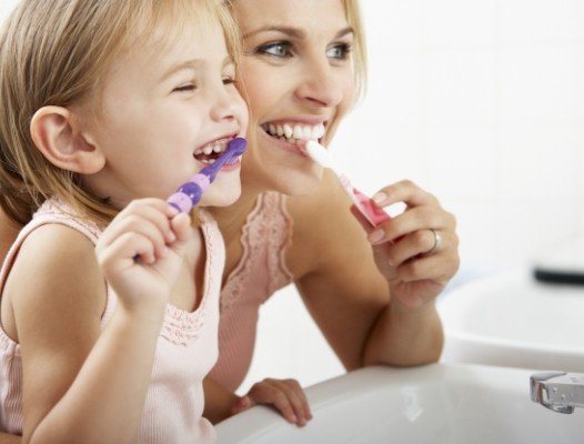 Mother and daughter brushing teeth to prevent tooth decay
