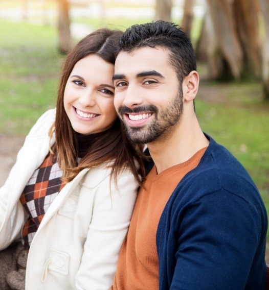 Man and woman smiling after dental implant tooth replacement