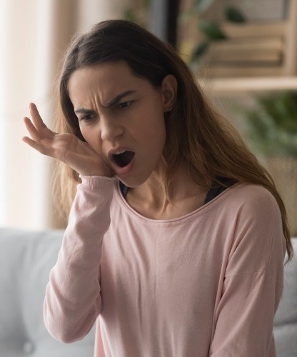 Woman in need of T M J therapy holding jaw in pain