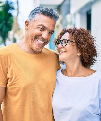 Man and woman sharing healthy smiles after dental implant tooth replacement