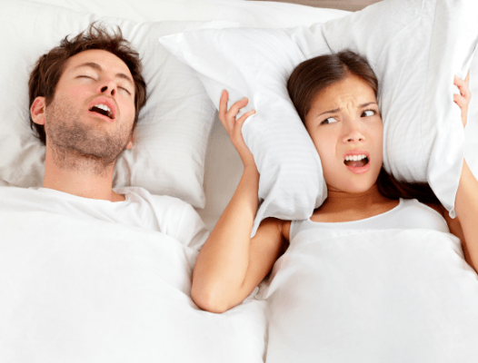 Frustrated woman in bed next to snoring man
