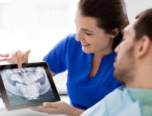 Dental team member and patient looking at digital x-rays