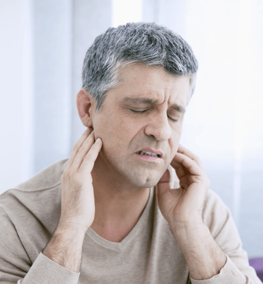 Man in need of T M J therapy holding jaw in pain