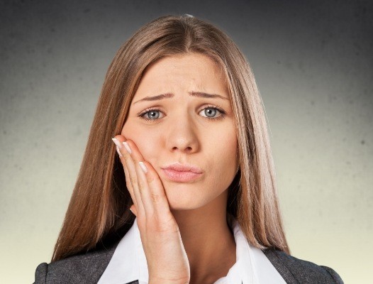 Woman with a dental cavity holding cheek in pain