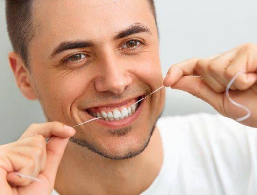 Man flossing teeth to care for tooth colored fillings