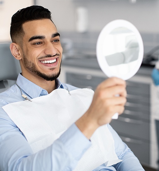 a dental patient looking in a mirror and smiling
