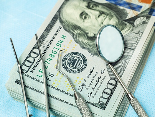 stack of money with dental instruments on top