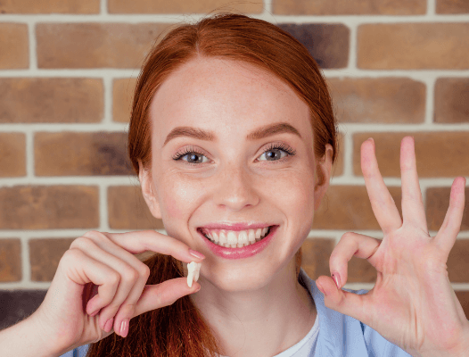 Woman holding up extracted wisdom tooth