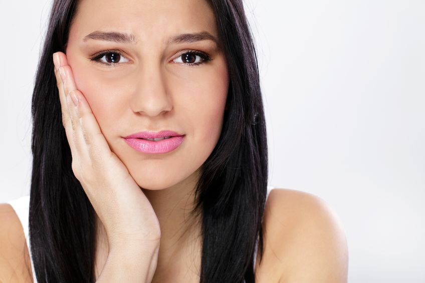 teenager holding side of face in pain