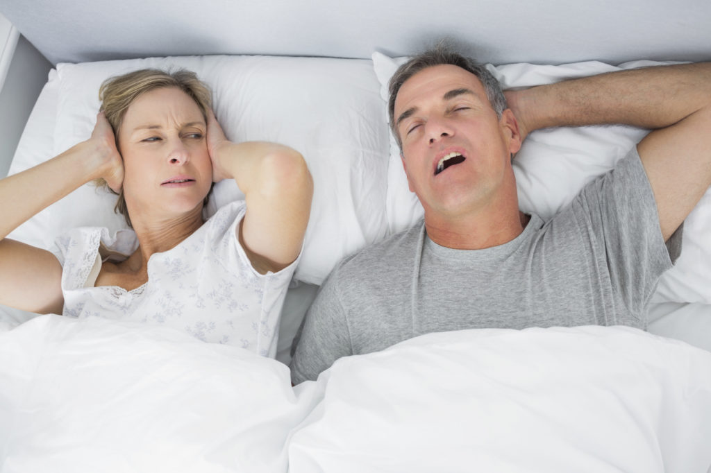 man snoring next to unhappy woman