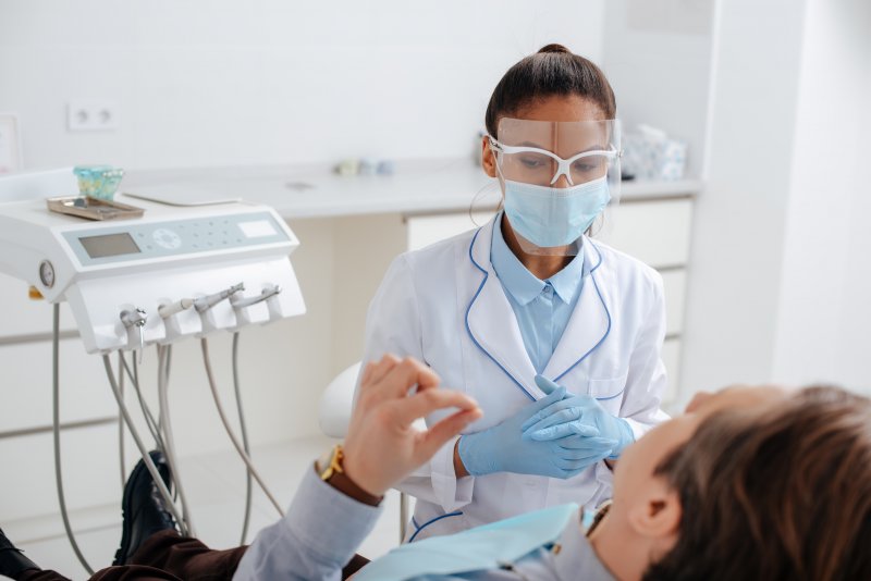 a female dentist preparing to examine a male patient’s smile