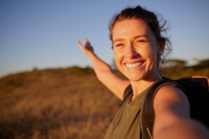 a smiling woman taking a selfie while hiking