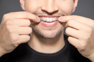 a man putting a whitening strip over his top row of teeth