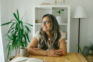 a smiling woman sitting in her living room at a table